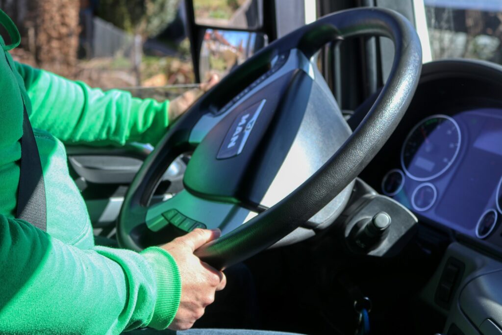 Close-up of a truck driver's hands on the steering wheel inside a semi-truck cab, representing common challenges like back strain and fatigue for commercial drivers and how chiropractic care helps them stay well on the road at ChiroCure Health Center in Jacksonville, FL