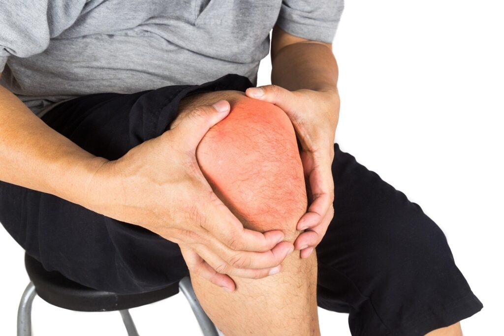 Person clutching painful knee with glowing red joint overlay, illustrating winter knee pain spikes and inflammation helped by chiropractic care at ChiroCure Health Center